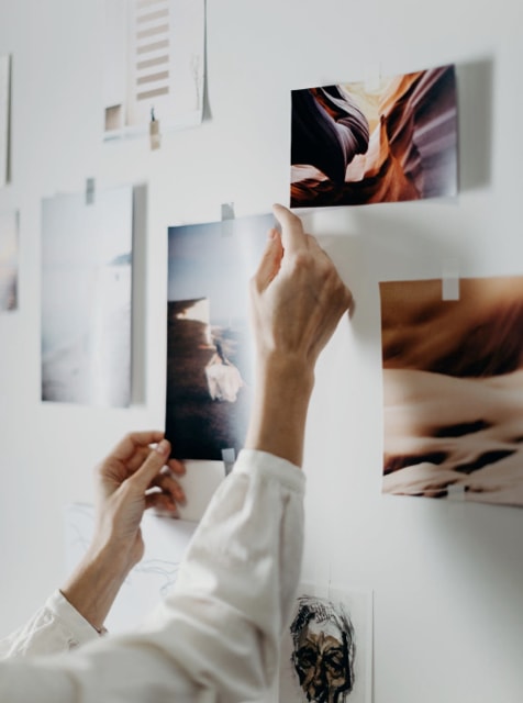 Woman's hands reaching out for an art piece on the wall
