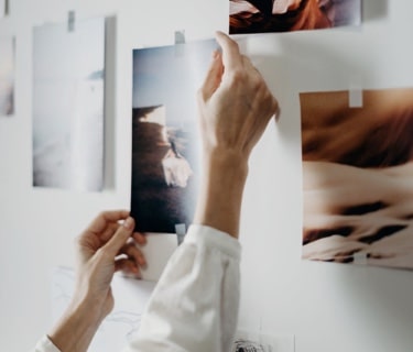 Woman's hands reaching out for an art piece on the wall