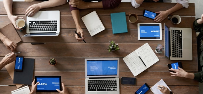 Birds-eye view of a collaborative gathering of people working on laptops and tablets.