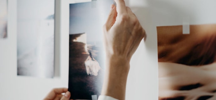 Woman's hands reaching out for an art piece on the wall